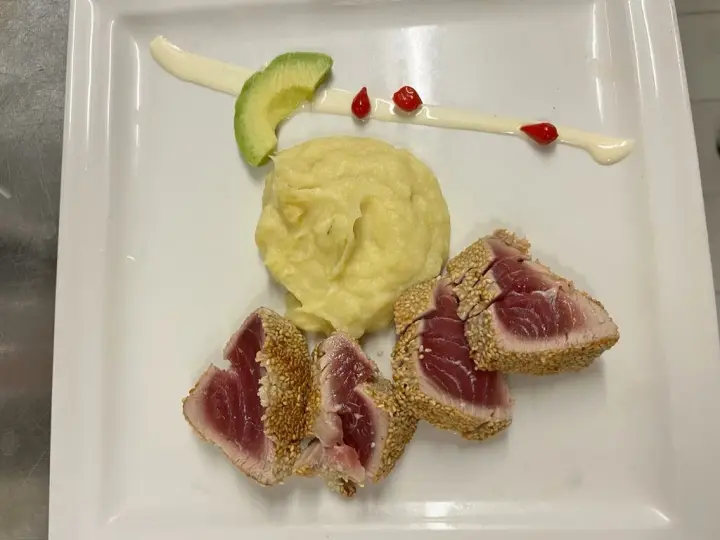 Rosa gebratener Thunfisch mit Püree und Avocado auf weißem Teller